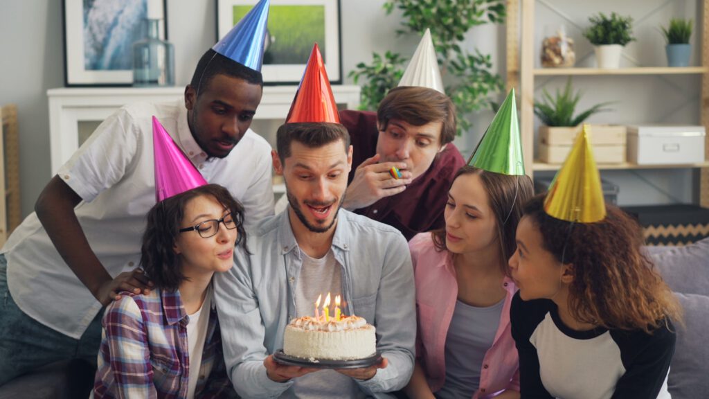 a group of people standing around a cake with candles on it